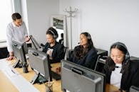A diverse team of customer service representatives working in an office setting, wearing headsets and using computers.